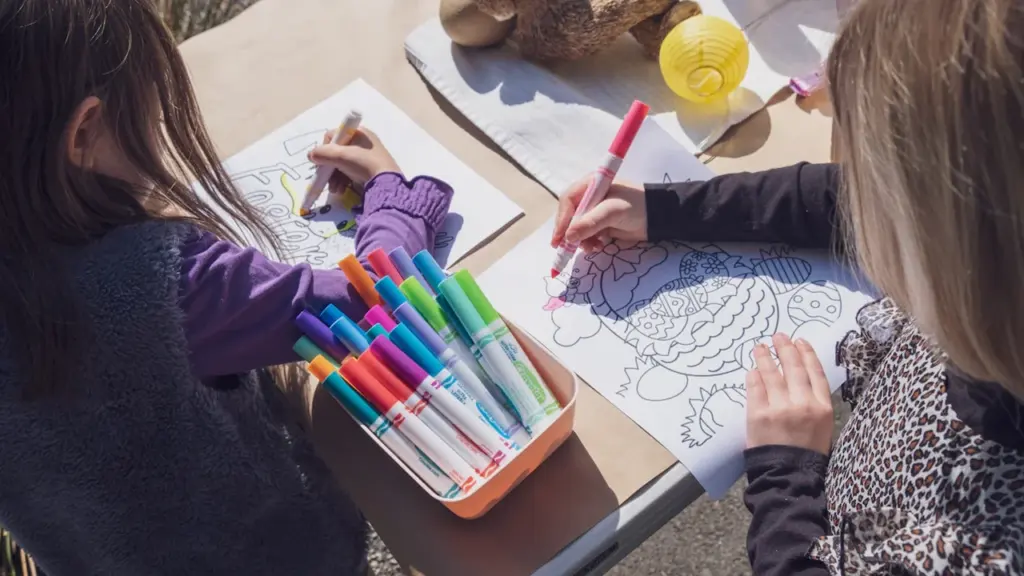 Zwei Kinder sitzen am Tisch und malen gemeinsam mit bunten Filzstiften kreative Bilder.