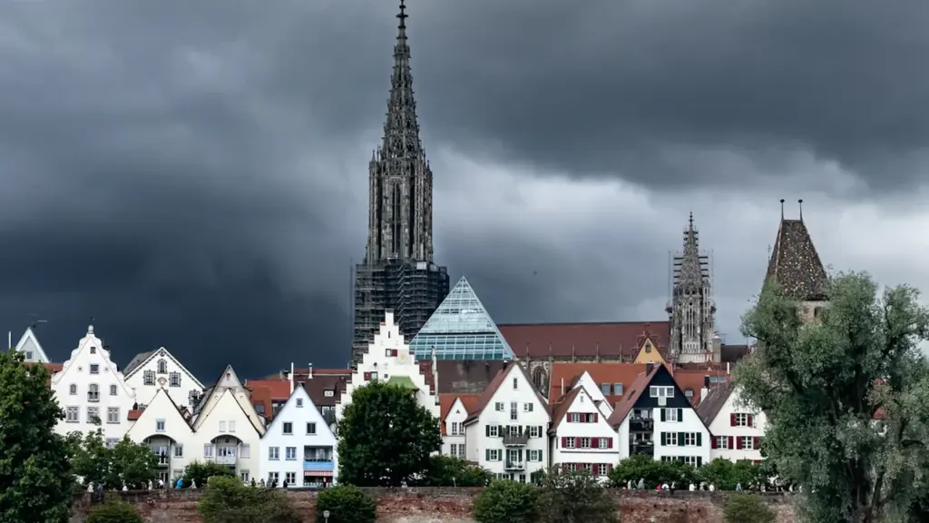 Panoramablick auf das Ulmer Münster und die Altstadt an der Donau bei bewölktem Himmel.