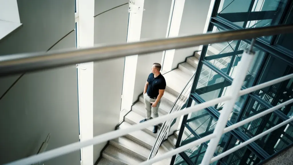 Ein Mann nimmt eine aktive Bewegungspause auf einer modernen Büro-Treppe im Glasgebäude.