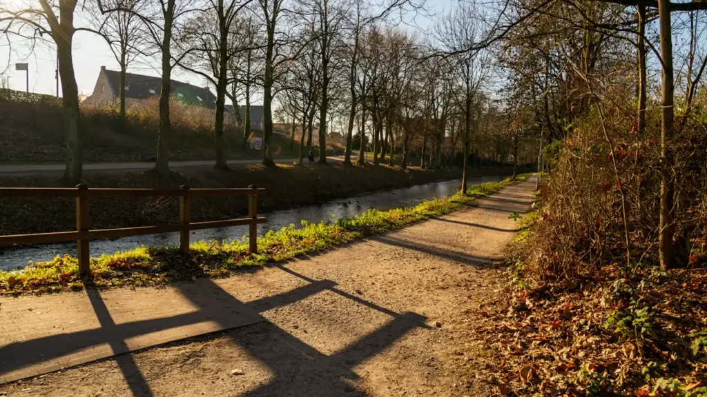 Ein sonniger Herbstweg entlang eines Kanals in einer typisch deutschen Stadt.