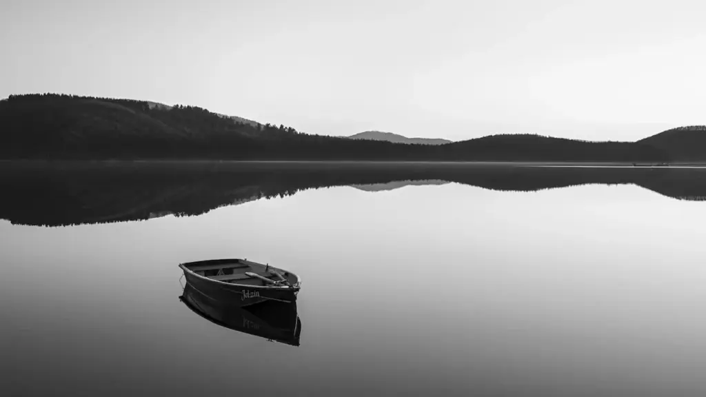 Ein einsames Ruderboot auf einem spiegelglatten See vor einer ruhigen Bergkulisse in Deutschland.