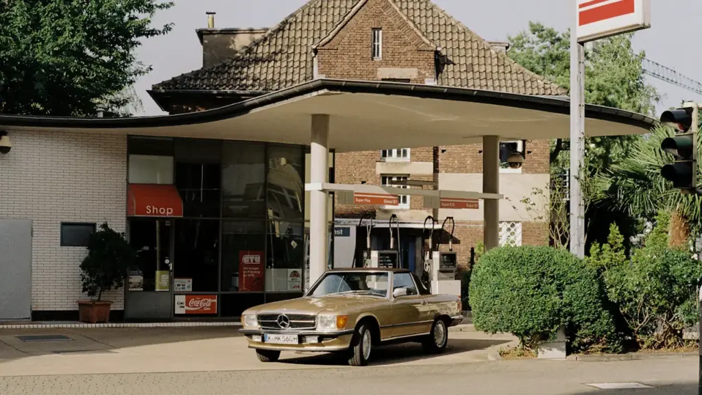 Ein klassisches Auto an einer Tankstelle in einer deutschen Stadt bei Tageslicht.