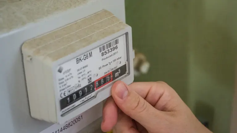 Eine Hand beim Ablesen eines Stromzählers zur Überprüfung des Verbrauchs.