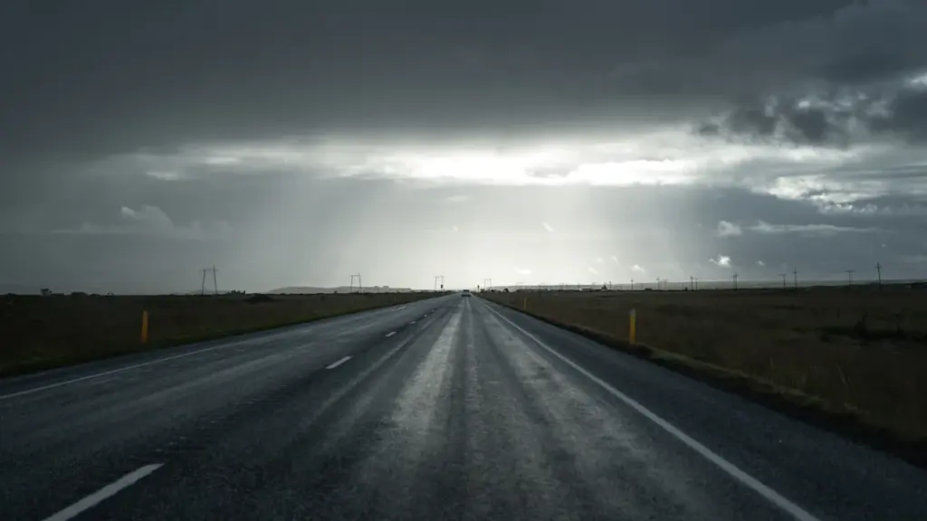Eine nasse Autobahn unter einem stürmischen und bedrohlich wirkenden grauen Himmel.